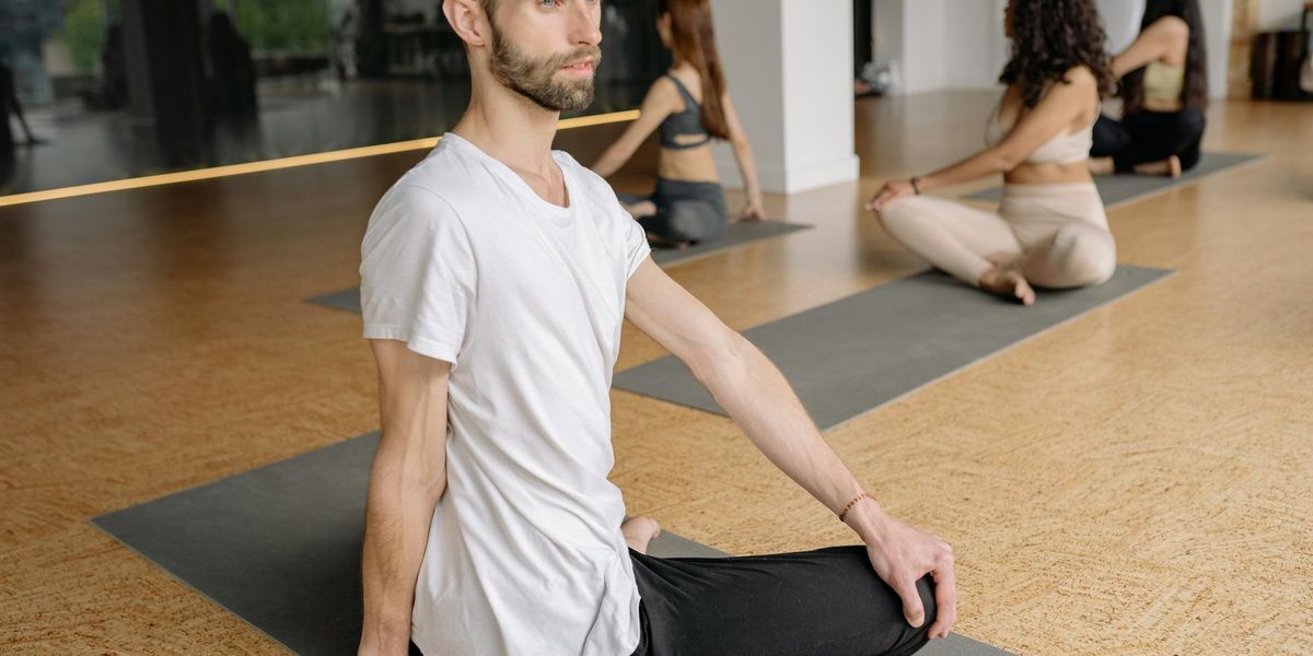 Group of people sitting in circle on yoga mats indoors